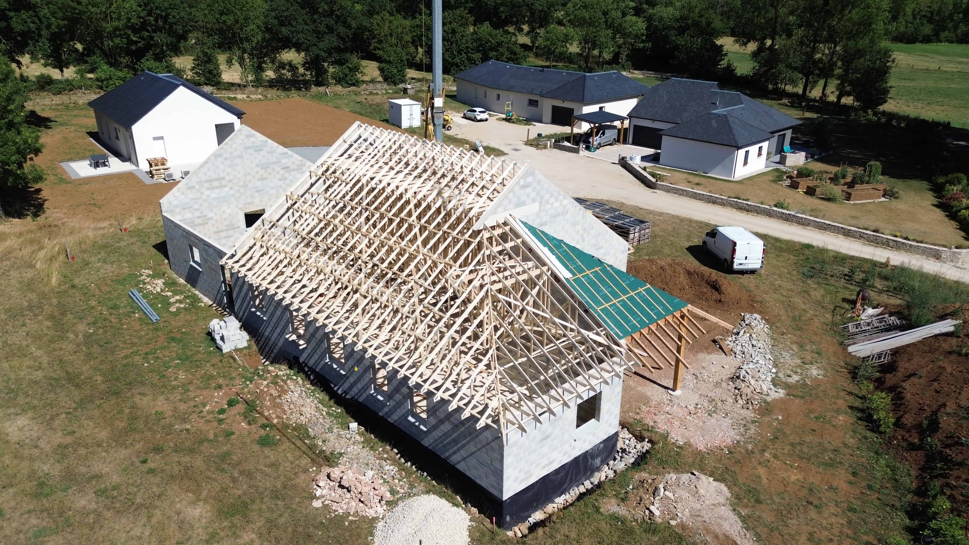Maison en construction avec charpente en bois visible.