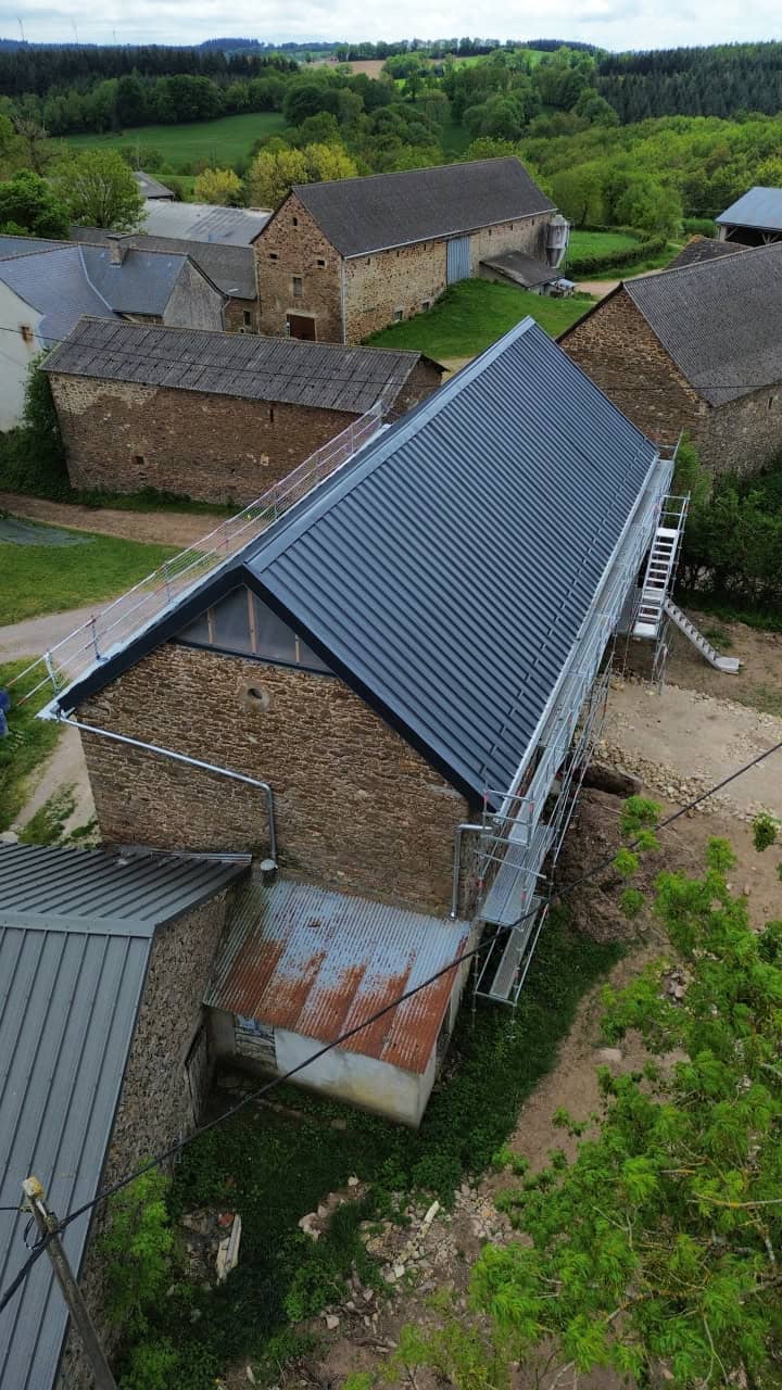 Rénovation de bâtiments en bois traditionnels avec toiture en métal dans un village rural.