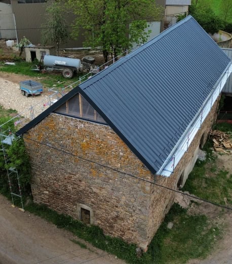 Rénovation et construction en bois, maison en pierre, toiture métallique.
